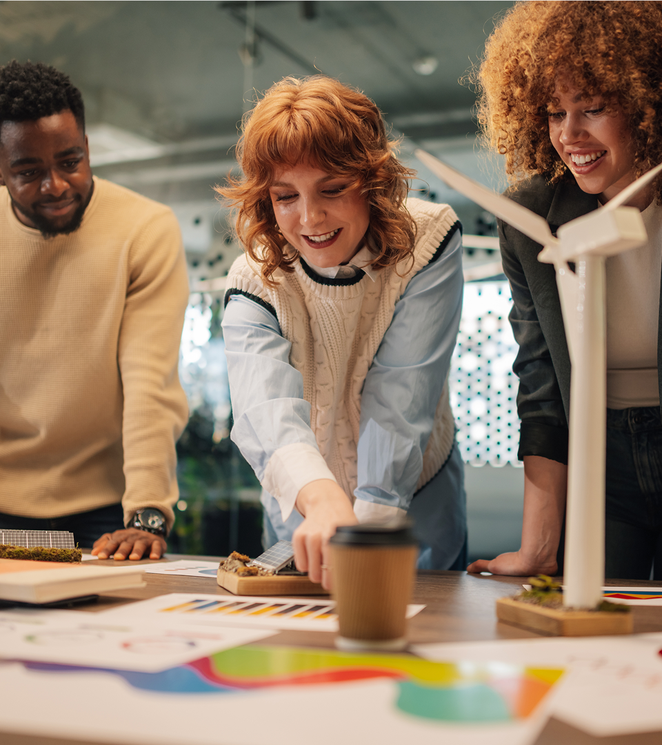 Group of colleagues reviewing colourful design materials around a table in a creative workspace.